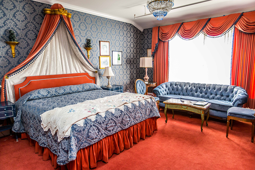 Image of Suite at the Grand Hotel with navy blue duvet covers and canopy overhead. Grand Hotel, a member of Historic Hotels since 2001, dates to 1886. It is located in Mackinac Island, Michigan.